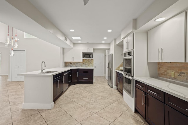 kitchen featuring sink, white cabinetry, appliances with stainless steel finishes, kitchen peninsula, and pendant lighting