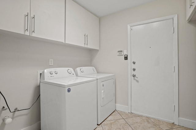 clothes washing area with cabinets, washing machine and dryer, and light tile patterned flooring