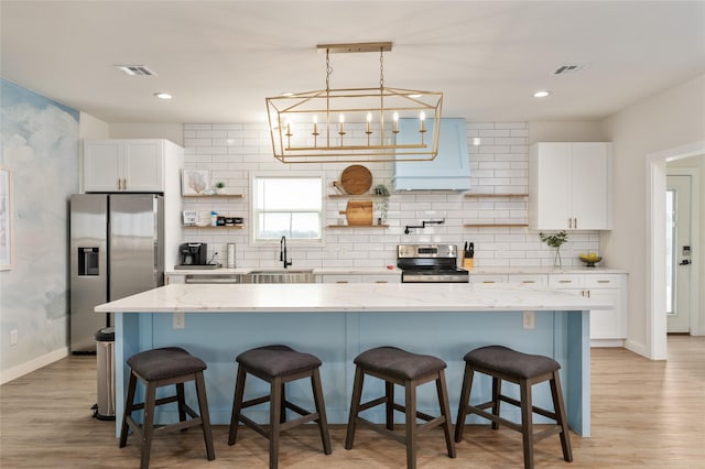 kitchen featuring appliances with stainless steel finishes, a center island, white cabinets, and a kitchen bar