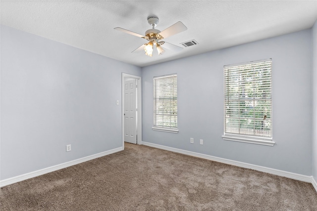 carpeted empty room featuring a ceiling fan, a healthy amount of sunlight, visible vents, and baseboards