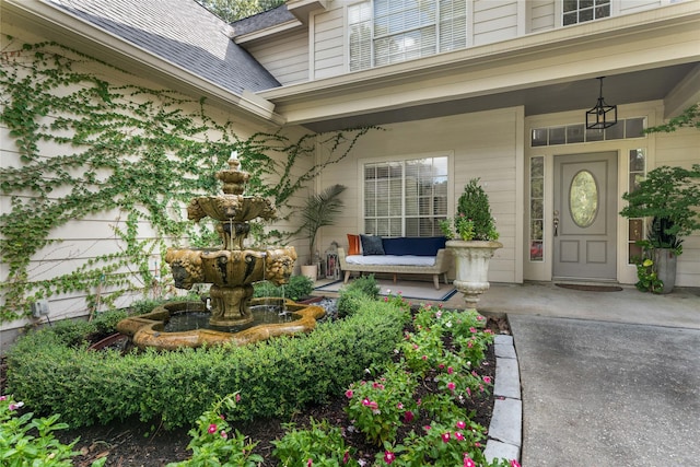 doorway to property featuring covered porch and a shingled roof