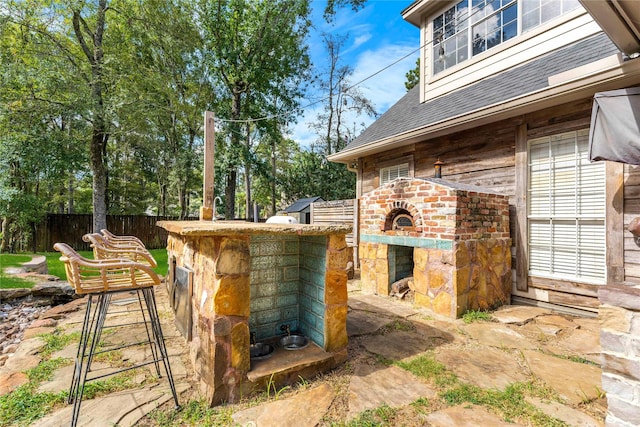 view of patio featuring an outdoor brick fireplace and fence