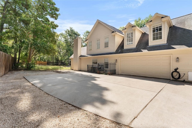 view of home's exterior featuring concrete driveway, roof with shingles, an attached garage, and fence