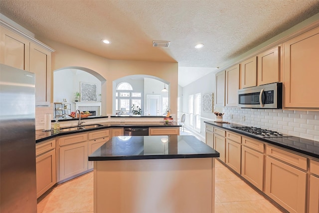 kitchen featuring light tile patterned flooring, a kitchen island, appliances with stainless steel finishes, light brown cabinetry, and sink