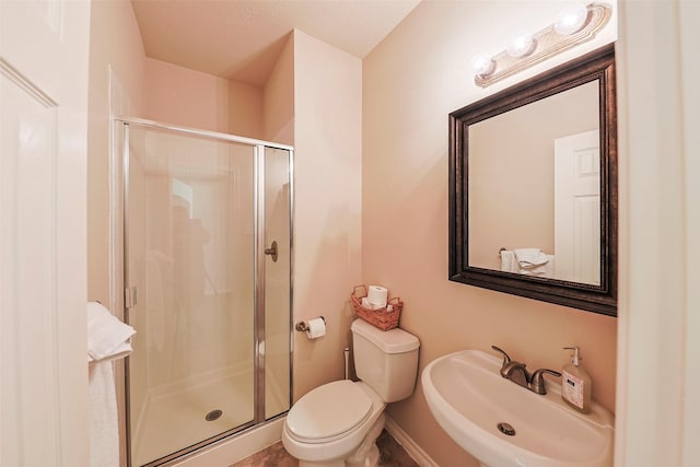 bathroom featuring toilet, a shower with door, and sink