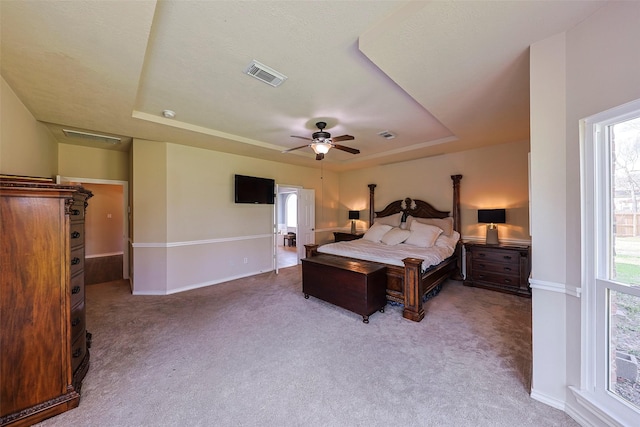 carpeted bedroom featuring ceiling fan, a raised ceiling, and multiple windows