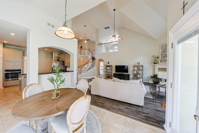 dining room featuring light tile patterned floors, high vaulted ceiling, and ceiling fan