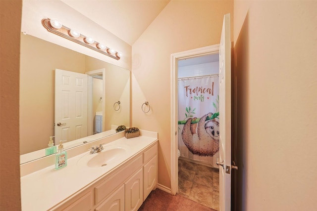 bathroom featuring lofted ceiling, toilet, and vanity