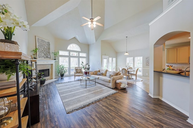 living room featuring ceiling fan, high vaulted ceiling, a fireplace, and dark hardwood / wood-style flooring