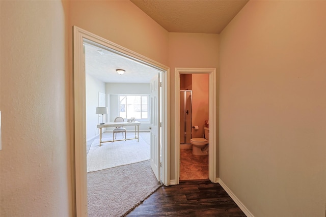 corridor with dark hardwood / wood-style flooring and a textured ceiling