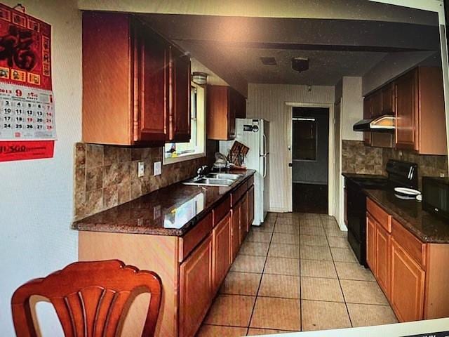 kitchen with sink, backsplash, fridge, light tile patterned floors, and black electric range