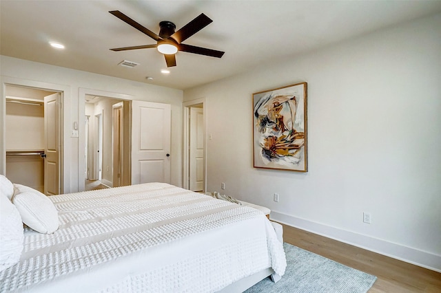 bedroom featuring ceiling fan, wood-type flooring, a spacious closet, and a closet