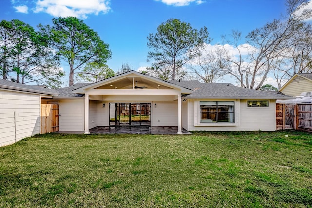 rear view of house with ceiling fan, a patio area, and a lawn