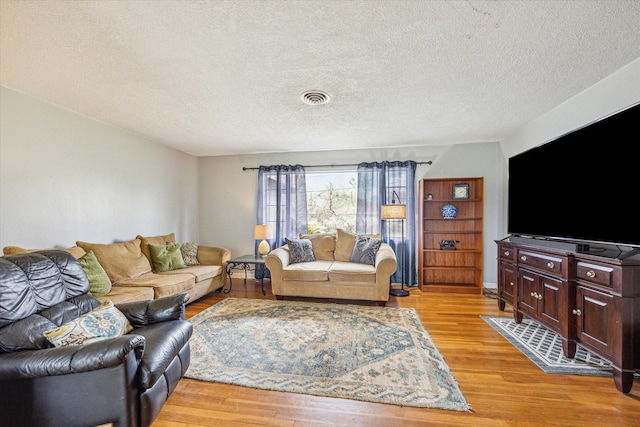 living room with a textured ceiling and light wood-type flooring