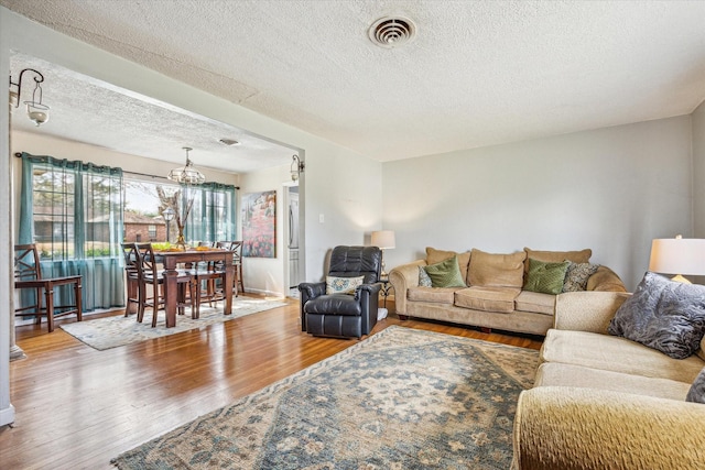 living room with hardwood / wood-style flooring, an inviting chandelier, and a textured ceiling