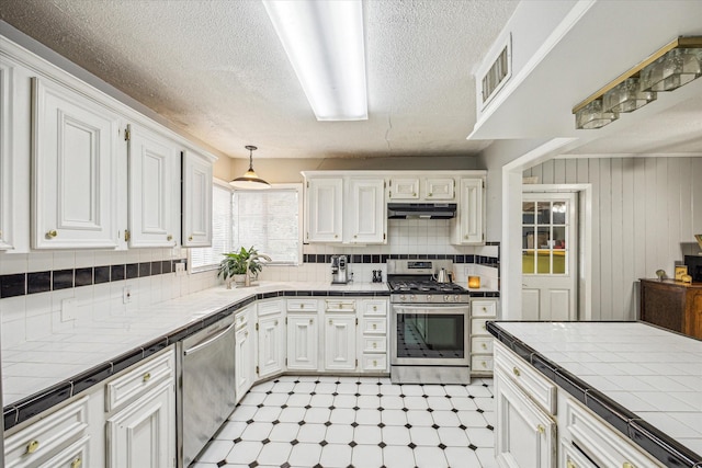 kitchen featuring appliances with stainless steel finishes, tile countertops, and white cabinets