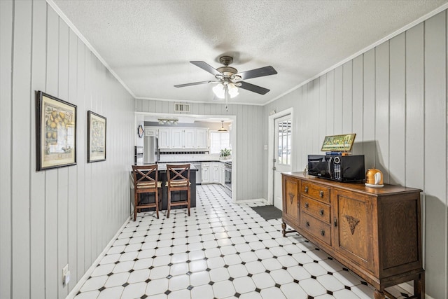 interior space with crown molding, ceiling fan, and a textured ceiling