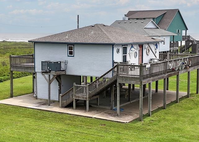 back of property with a wooden deck, central AC, a lawn, and a patio area