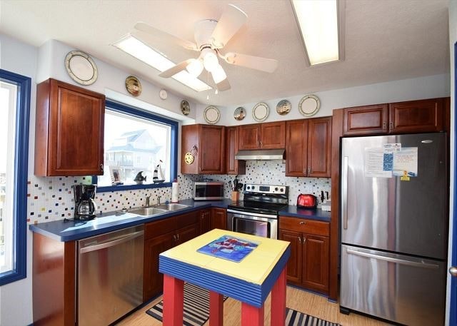 kitchen featuring sink, tasteful backsplash, light wood-type flooring, ceiling fan, and stainless steel appliances