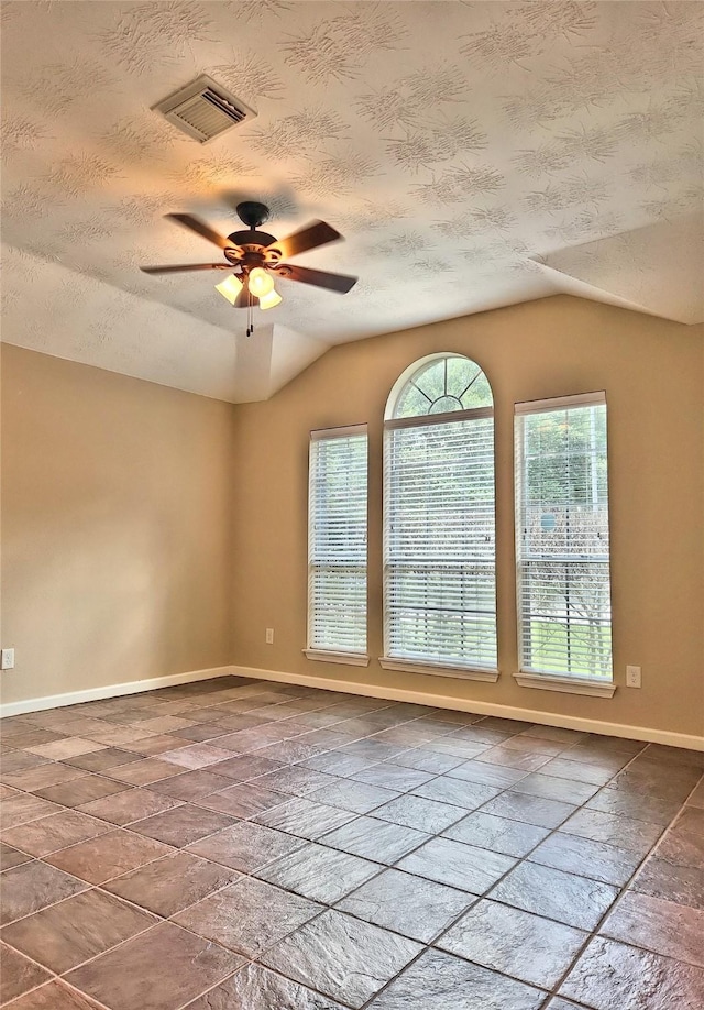 spare room featuring ceiling fan, lofted ceiling, and a textured ceiling