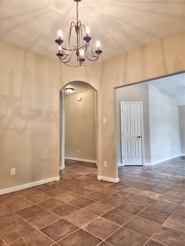 unfurnished room featuring an inviting chandelier and a textured ceiling