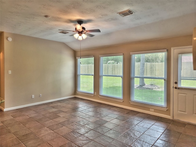 spare room with ceiling fan, vaulted ceiling, and a textured ceiling