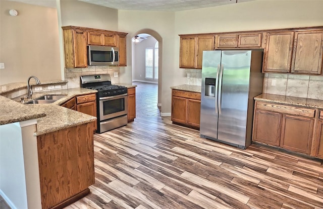 kitchen with light stone counters, sink, kitchen peninsula, and appliances with stainless steel finishes