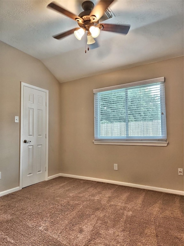 empty room featuring vaulted ceiling, carpet flooring, a textured ceiling, and ceiling fan