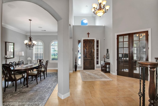 foyer featuring a notable chandelier, ornamental molding, french doors, and a high ceiling