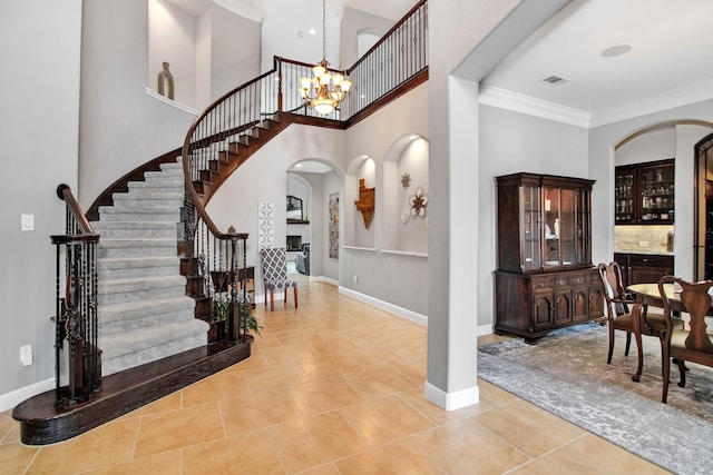 entrance foyer featuring a high ceiling, crown molding, light tile patterned floors, and a chandelier