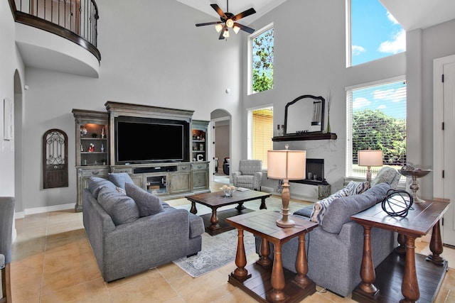 living room featuring ceiling fan, a premium fireplace, a high ceiling, and light tile patterned floors