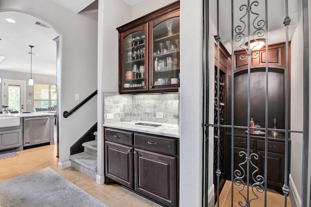 bar with sink, dishwasher, hanging light fixtures, backsplash, and dark brown cabinets