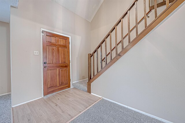 carpeted foyer entrance featuring lofted ceiling