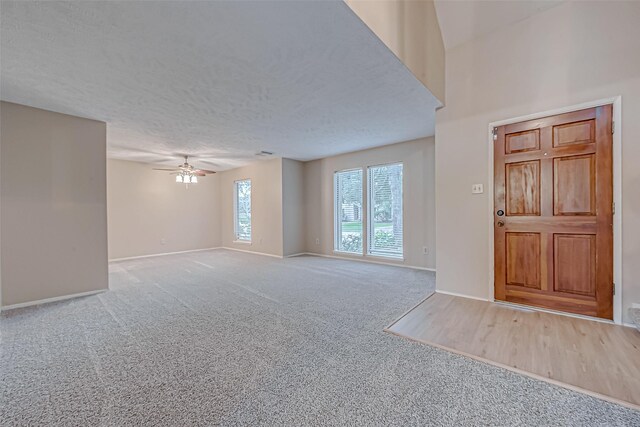 entryway with baseboards, a textured ceiling, carpet, and a ceiling fan