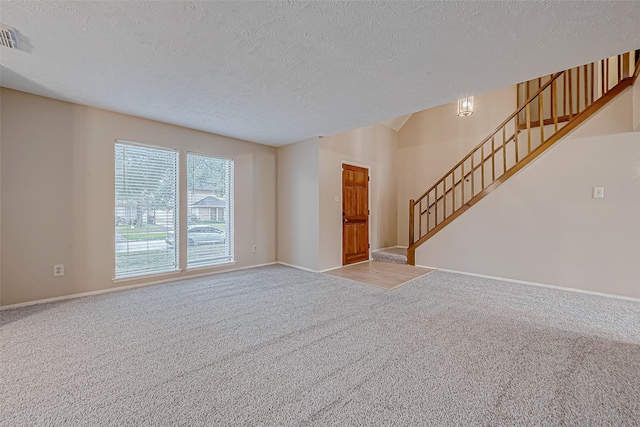 unfurnished living room with carpet floors and a textured ceiling