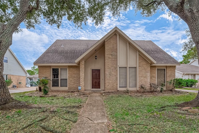 mid-century home featuring brick siding, a front yard, and roof with shingles