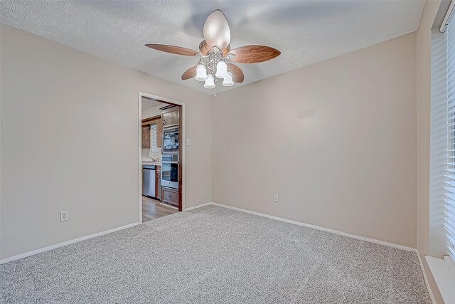 empty room featuring ceiling fan, light colored carpet, sink, and a textured ceiling