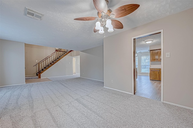 unfurnished living room featuring visible vents, baseboards, carpet, stairway, and a textured ceiling