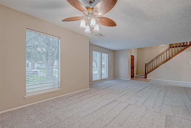 unfurnished room with visible vents, a textured ceiling, carpet flooring, and stairway