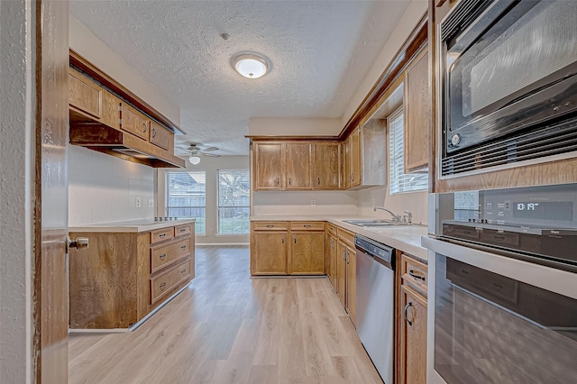 kitchen featuring sink, ceiling fan, black appliances, a textured ceiling, and light hardwood / wood-style flooring