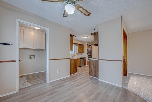 kitchen featuring dishwasher, sink, a textured ceiling, and light hardwood / wood-style flooring