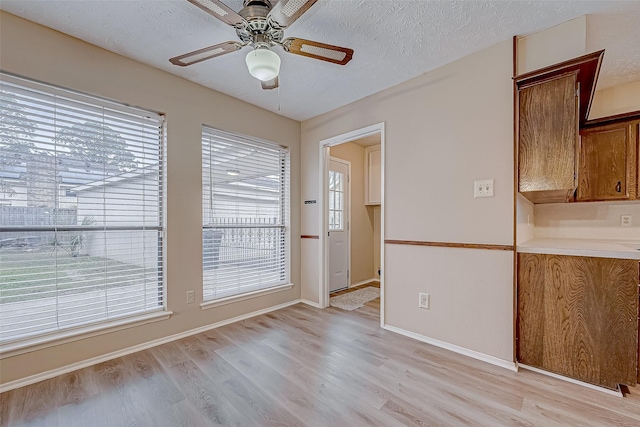 interior space featuring ceiling fan, light hardwood / wood-style floors, and a textured ceiling