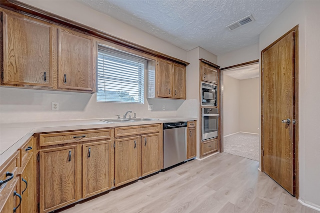 kitchen with stainless steel appliances, light hardwood / wood-style floors, sink, and a textured ceiling