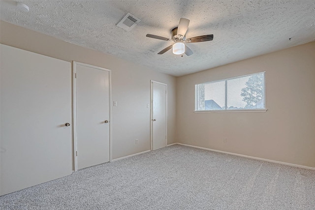 unfurnished bedroom featuring ceiling fan, carpet flooring, and a textured ceiling