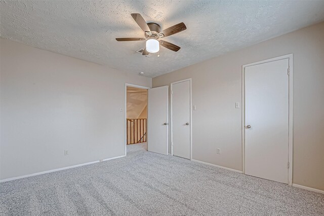 unfurnished bedroom featuring ceiling fan, light colored carpet, and a textured ceiling