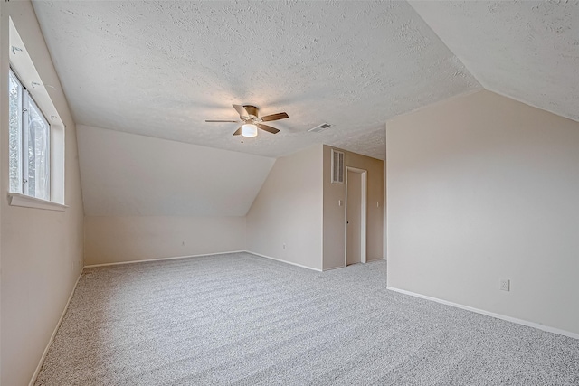 additional living space with visible vents, carpet, and vaulted ceiling