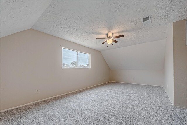 bonus room featuring vaulted ceiling, carpet, a textured ceiling, and ceiling fan