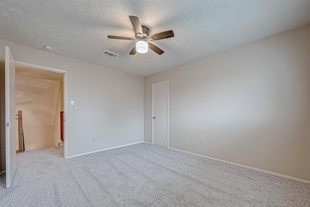 carpeted empty room featuring baseboards, visible vents, a textured ceiling, and ceiling fan