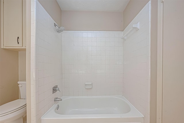 bathroom with toilet, tiled shower / bath combo, and a textured ceiling