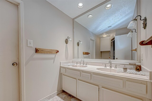 bathroom with vaulted ceiling, vanity, and a textured ceiling